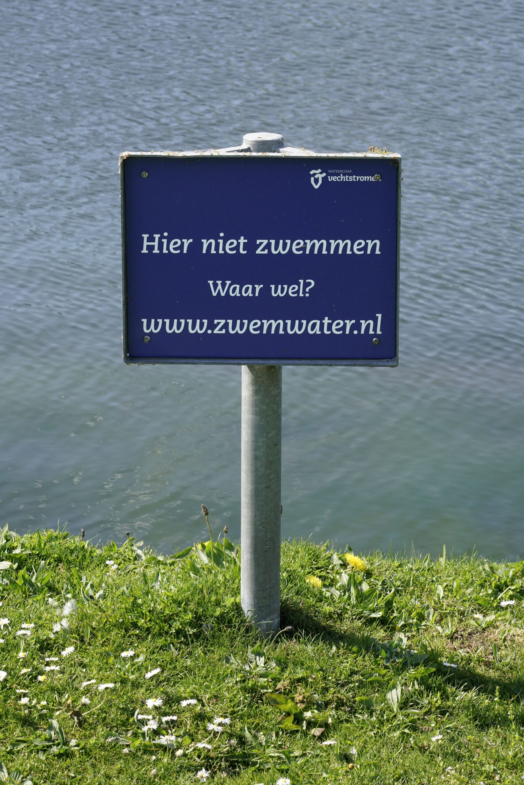 Waarschuwingsbord met tekst Hier niet zwemmen. Waar wel? www.zwemwater.nl