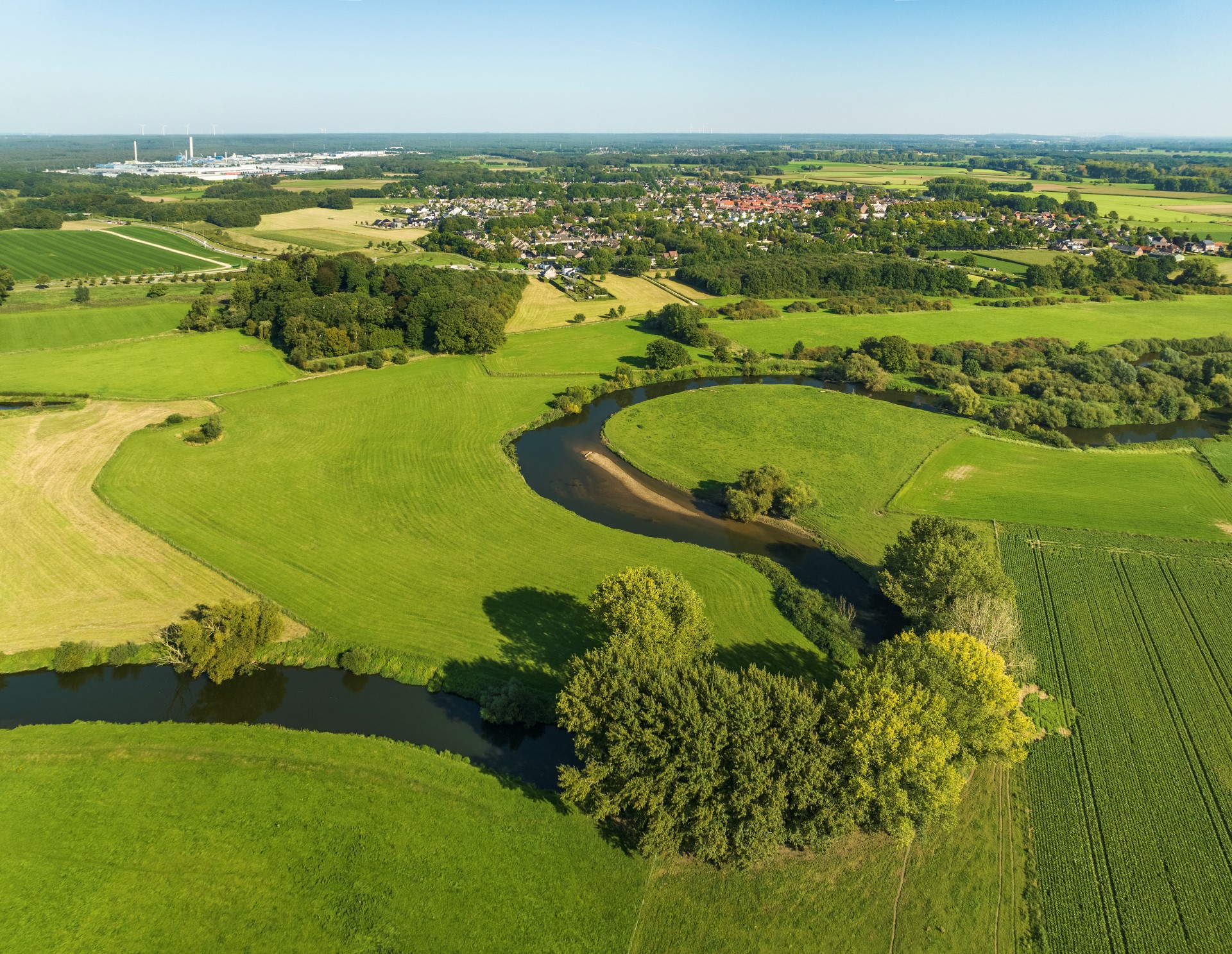 Foto van een groen landschap waar een rivier doorheen meandert. Deze rivier functioneert waarschijnlijk als een natuurlijke grens van een home range maar kan hij oversteken mocht dat nodig zijn. 